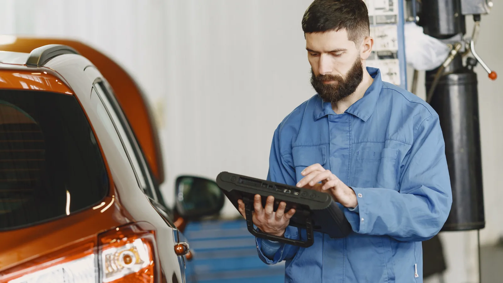 Professional mechanic using a diagnostic tablet beside a vehicle