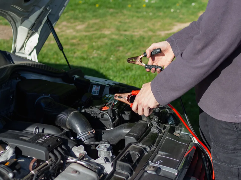 Person connecting jumper cables to a vehicle battery
