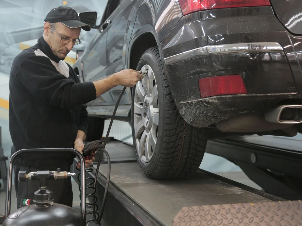 Mechanic checking tire pressure in an automotive workshop